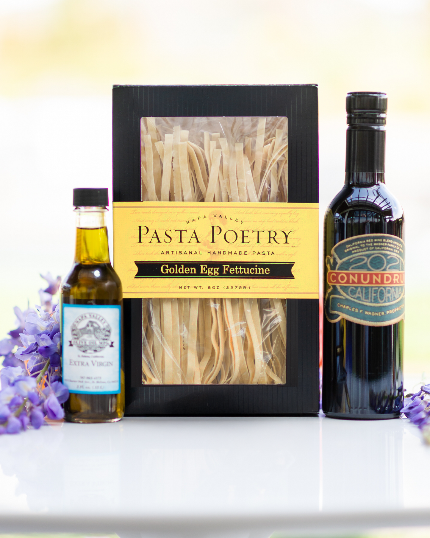 Pasta Poetry box with Conundrum olive oil on a white surface with blurred background